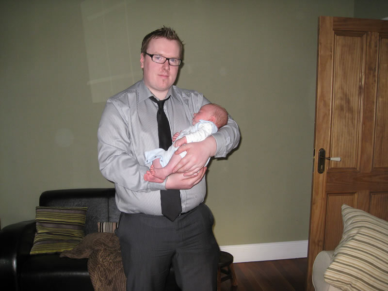 A parent holding a newborn indoors.