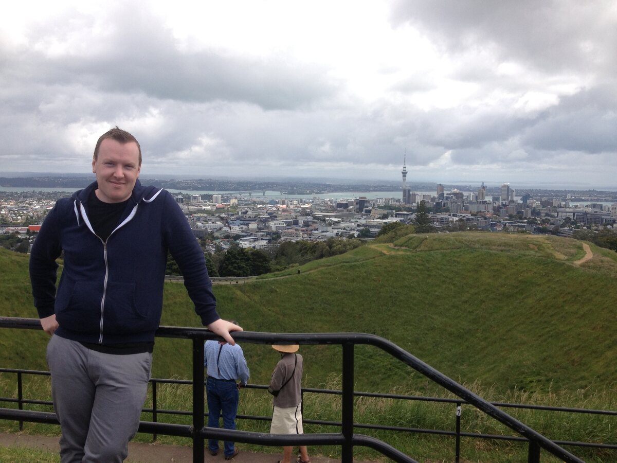 A person looking out over a city from a green hill.